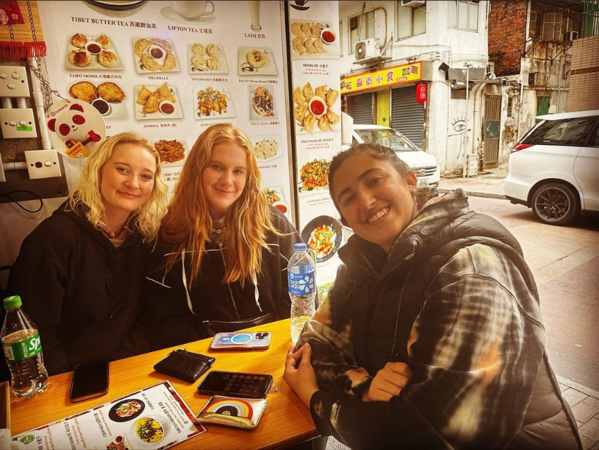 Satisfied customers smiling while waiting for food at My Kitchen HK in an outdoor daytime setting.